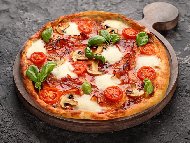 Рецепта Домашна пица с доматен сос, прошуто, гъби, моцарела и чери домати на плоча